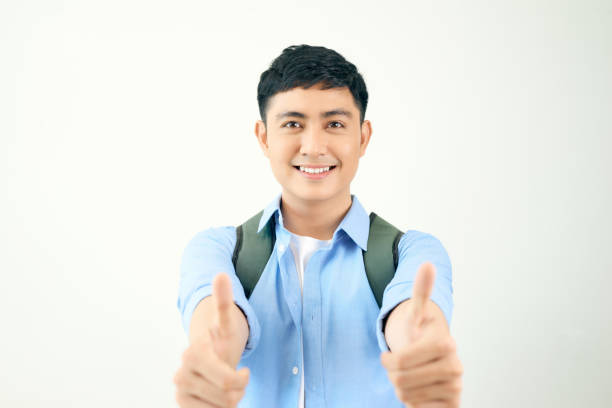 istock Young student man with backpack bag holding two hands with thumb up gesture on white background 1220106459