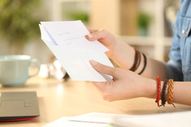 estudante mão menina colocando carta em um envelope em casa - handwriting correspondence writing women - fotografias e filmes do acervo