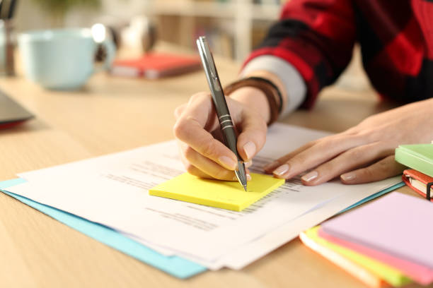 istock Student girl hand writing on post note at home 1220106585