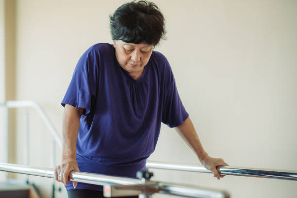 Asian chinese senior women practicing, holding parallel bars and walking in a rehab centre at hospital mujeres de la tercera edad chinas asiáticas practicando, sosteniendo bares paralelos y caminando en un centro de rehabilitación en el hospitalmujeres de la tercera edad chinas asiáticas que sostienen bares paralelos y caminan en un centro de rehabilitac
