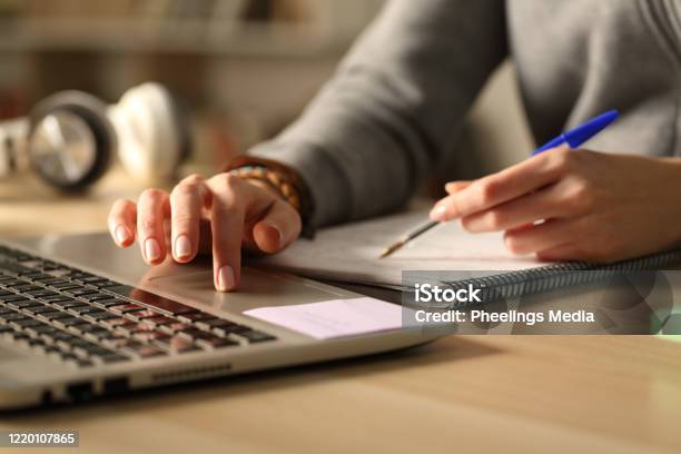 Student Hands Comparing Laptop Content And Notes At Night Stock Photo - Download Image Now