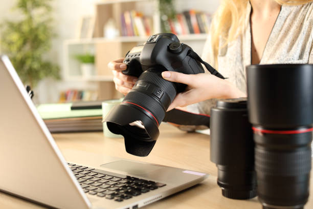 Photographer hands with laptop checking camera Close up of photographer woman hands with laptop checking dslr camera on a desk at home photographer stock pictures, royalty-free photos & images
