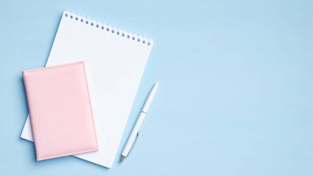 istock Blank notepad with pen and documents on blue background. Flat lay, top view office desk. Minimal style feminine workspace 1220108478