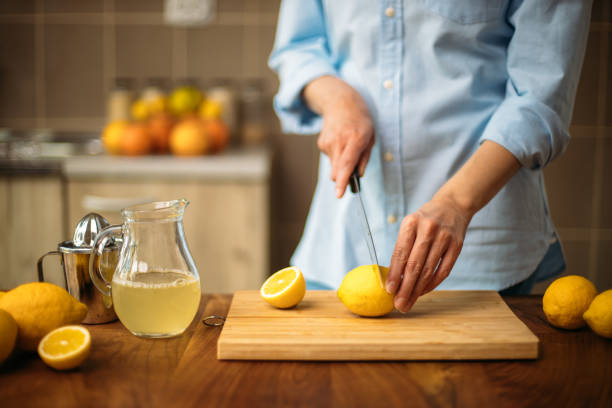 istock Young woman cutting lemon in the kitchen 1220110021