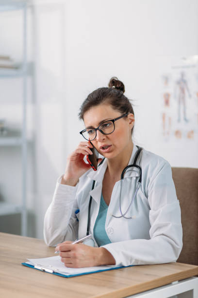 istock Female doctor taking a call from a patient during quarantine. Prescribing therapy from a remote medical office to isolated patient. 1220111079