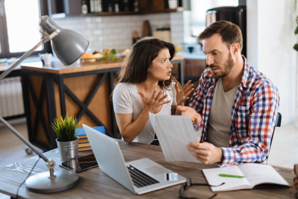 istock Frustrated couple checking bills at home using laptop 1220111831