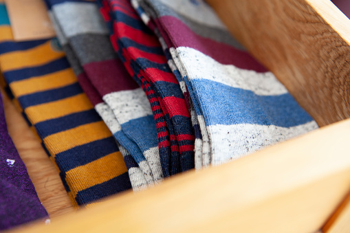 Different coloured striped socks in an open drawer