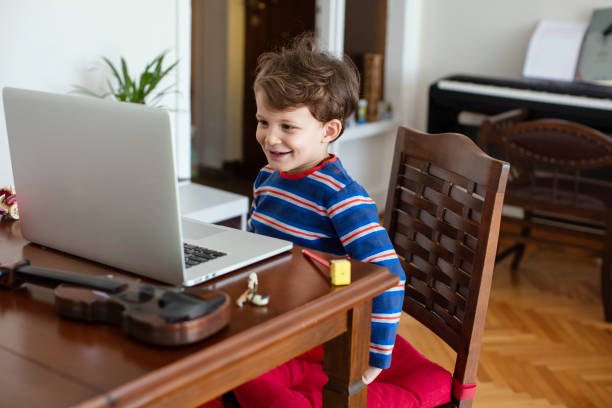 istock Little Child Smiling and Staring at the Computer during an Online Chat or Lesson 1220116394