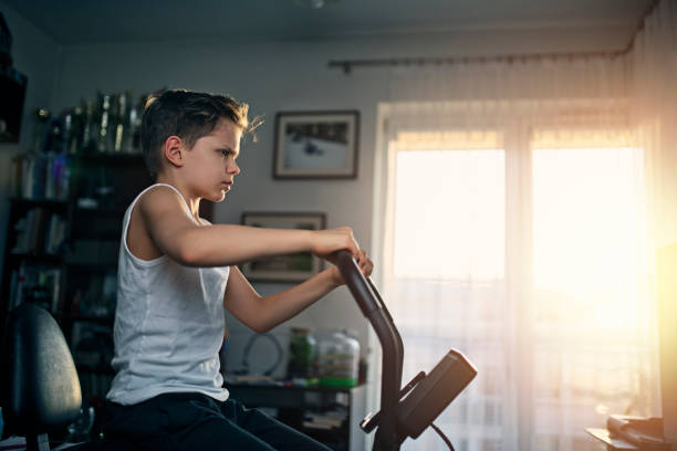 little boy working out on exercise bike at home - ten speed bicycle imagens e fotografias de stock