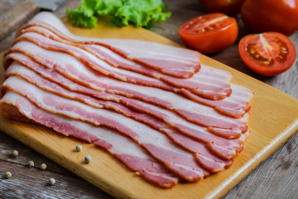 tocino en rodajas crudos sobre tabla de madera - tocino ahumado fotografías e imágenes de stock