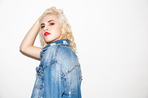 beautiful young blonde girl in a white T-shirt and denim jacket on a white background, studio fashion photo with copy space