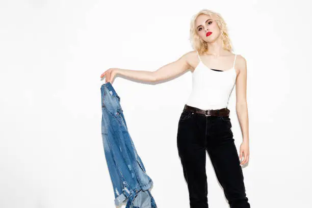 lovely young blonde girl in a white T-shirt and with denim jacket on a white background, studio fashion photo with copy space