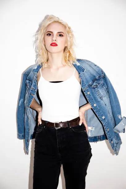 pretty young blonde girl in a white T-shirt and denim jacket on a white background, studio fashion photo