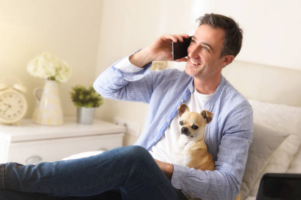 istock Man talking on the phone on a bed with dog 1220123614