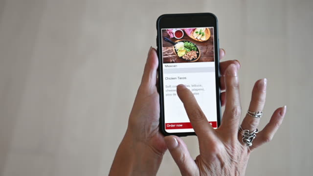 Mature woman alone Ordering Food Meal on mobile device app