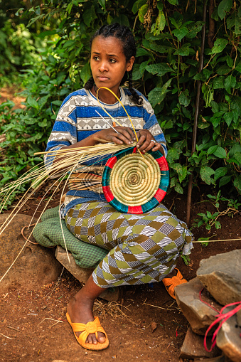 Young Ethiopian woman weaving a traditional food basket, cental Ethiopia, Africa.