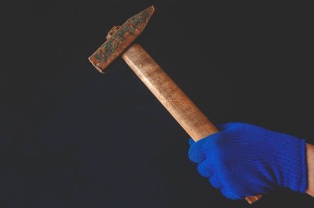 istock Men's hand in blue glove with hammer in hand 1220126725