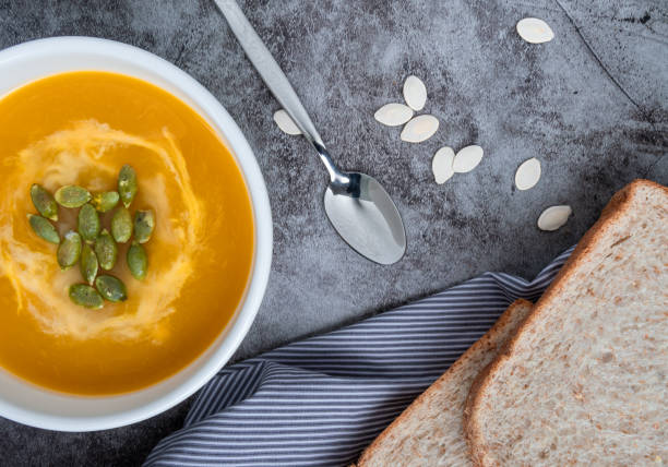 sopa de calabaza casera en un tazón con pan de trigo entero y semillas de calabaza, vista superior, espacio de copia. comida de otoño de temporada. comida vegana - pumpkin soup soup cup pumpkin fotografías e imágenes de stock