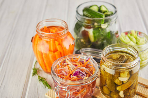 Fermented preserved vegetarian food concept Fermented preserved vegetarian food concept. Sour sauerkraut, pickled carrots, pickled cucumbers, pickled celery in glass jars on a white wooden kitchen table. The concept of canned food. Copy space pickled stock pictures, royalty-free photos & images