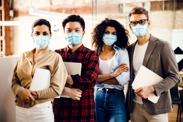 istock Multiracial young people in medical masks standing in office 1220128410