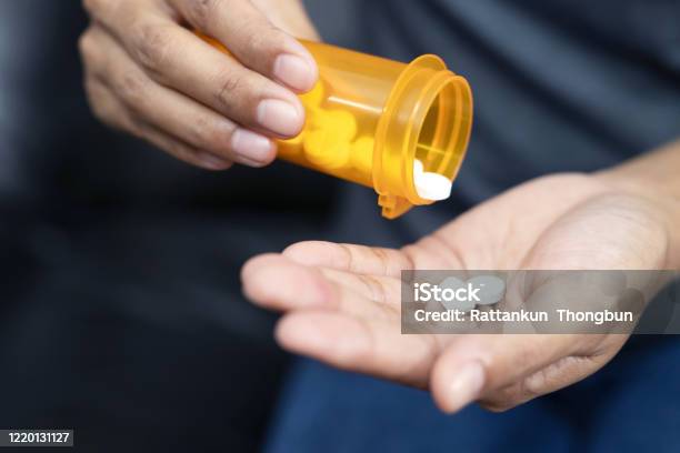 Woman Hand With Pills On Spilling Pills Out Of Bottle On Dark Background Stock Photo - Download Image Now