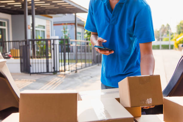 Asian delivery man courier online holding deliveries out boxes and using mobile phone contact the customer he protective face mask service under curfew quarantine pandemic coronavirus COVID-19 correo de entrega asiático en línea sosteniendo las cajas y utilizando el teléfono móvil póngase en contacto con el cliente que protector máscara de rostro servicio bajo el caso de la pandemia de cuarentena de toque de queda coronavirus covid-19