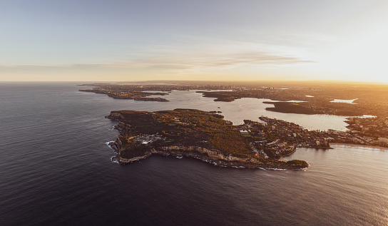 XXL panoramic sunset aerial drone view of North Head, a headland in Manly, Sydney, New South Wales, Australia. Manly Beach on right. Sydney Harbour with South Head, CBD & Harbour Bridge in background.