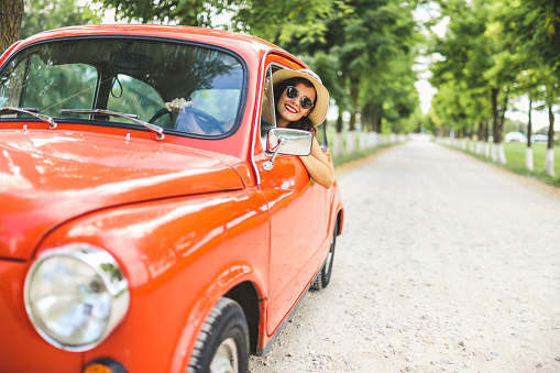 Young fashion woman driving red vintage car