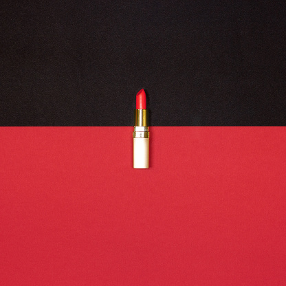 Red lipstick on black and red background - top view