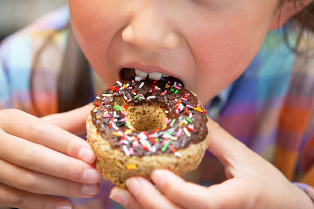 istock Child eating colorful chocolate donuts 1220143626