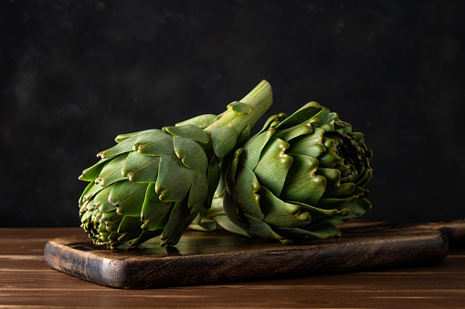 Ripe organic artichokes on a rustic wooden table. Vegetable background.