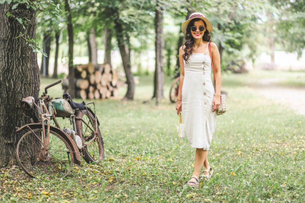 Old fashioned young woman near retro motorcycle outdoors