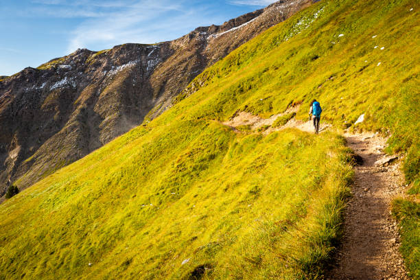 Woman backpacker tourist hiking walking alone mountain trail footpath lane  scenic alpine landscape view, South Tyrol alps solo travel Italy Europe tourism.