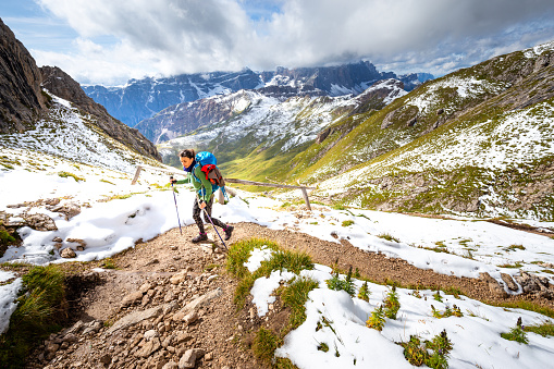 Woman backpacker tourist hiking walking ascending alone mountain trail footpath,   scenic landscape view, South Tyrol alps travel Italy solo Europe tourism.