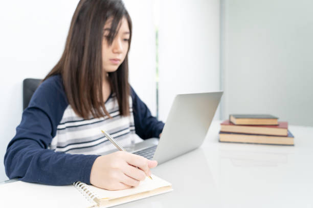 istock Young female student  sitting in living room and learning online 1220151156