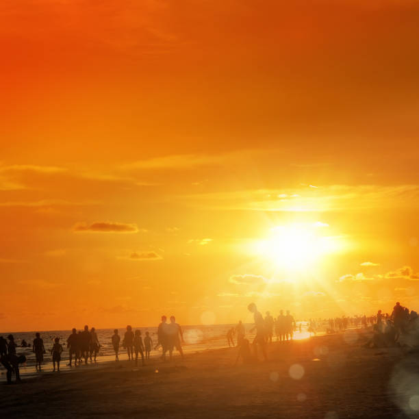 istock large group of silhouetted people on beach over orange color sunset 1220151561