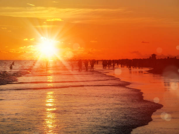 istock large group of silhouetted people on beach over orange color sunset 1220151578