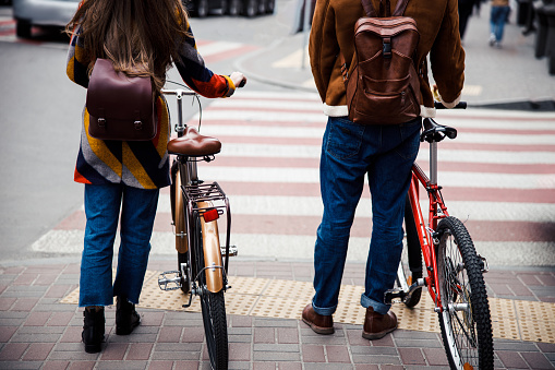Cropped photo of a man and a woman with bikes standing in front of a pedestrian crosswalk