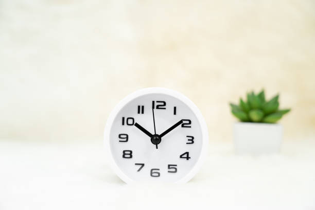istock White alarm clock and little decorative tree in vase on table 1220153477