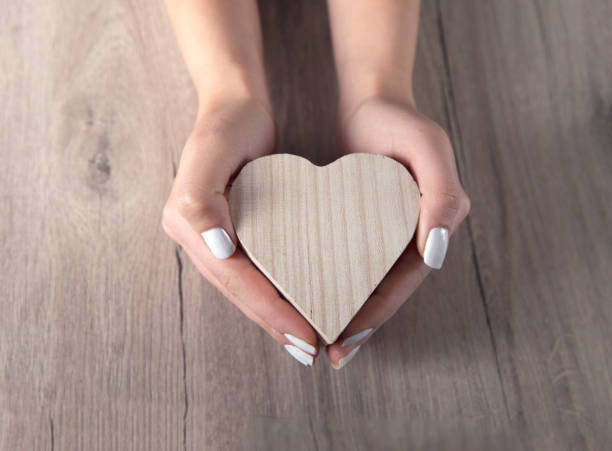 istock woman hand wooden heart 1220156479