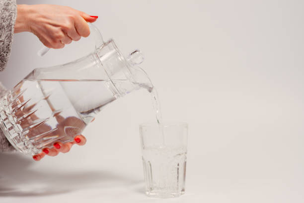 istock Drinking water. A female hand pours water from a decanter into a glass. 1220157868