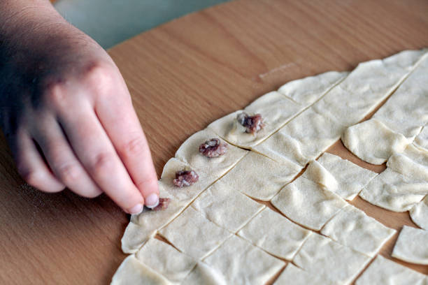 woman place minced meat each square dough part.  ingredients of manti are minced meat, parsley and onion. Manti is the Turkish style of dumpling or ravioli