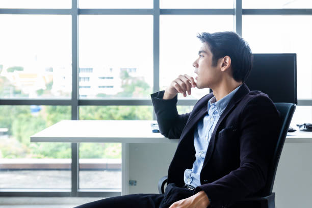 istock Young Asian businessman Sitting in a modern office is thinking and analyzing to find solutions to improve business performance 1220158071
