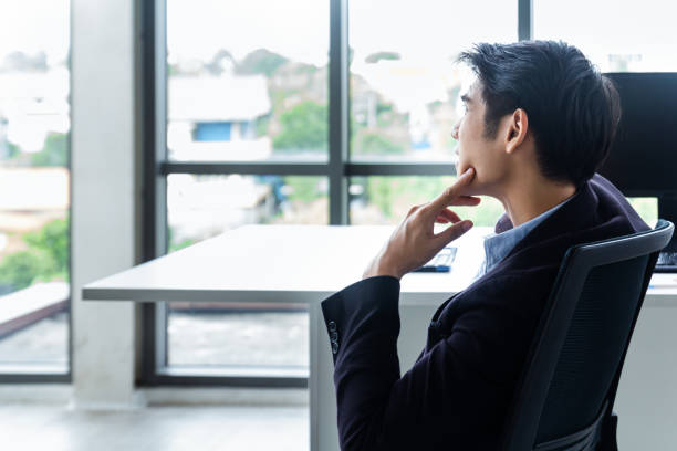 istock Young Asian businessman Sitting in a modern office is thinking and analyzing to find solutions to improve business performance 1220158126