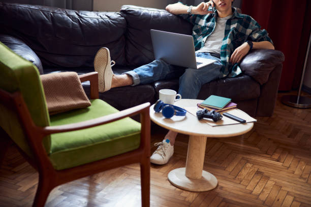 istock Young man resting on couch and talking on mobile phone 1220161579