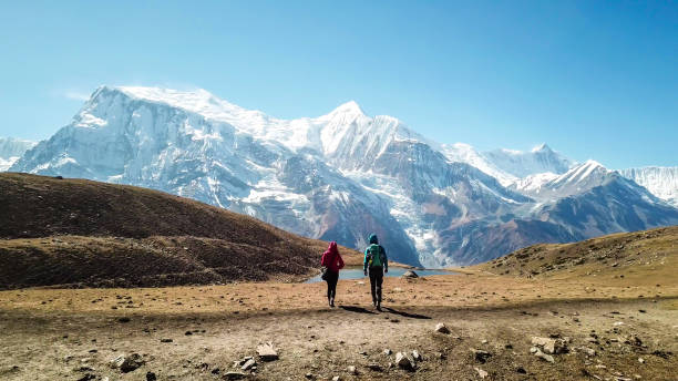 アイスレイク - アンナプルナチェーンの景色を眺め、アイスレイクに沿って歩いているカップル - glacier himalayas frozen lake ストックフォトと画像