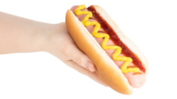 istock Hand holding hot dog with mustard isolated on white background. Clipping path 1220163902