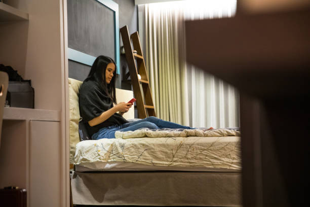 istock Asian woman relaxing on the bed at night texting on mobile 1220163951