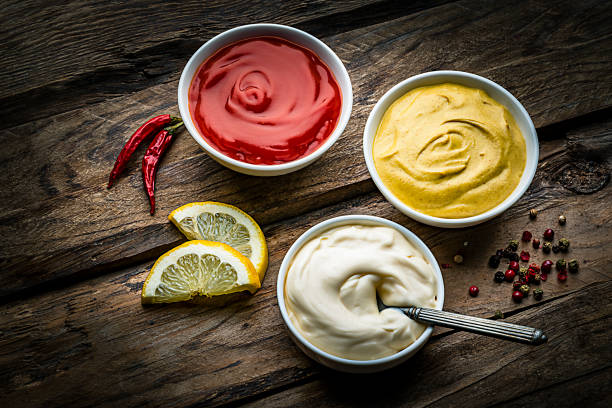 Ketchup, mustard and mayonnaise on rustic wooden table