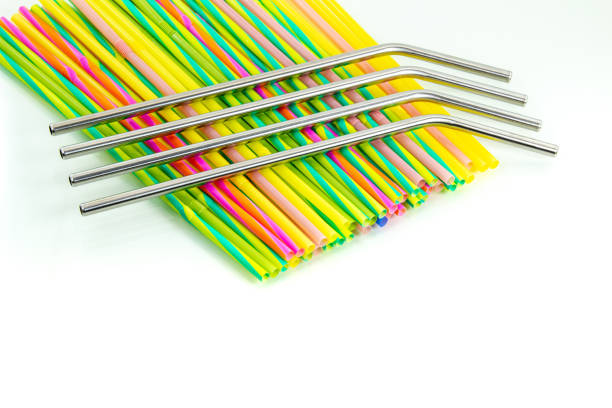 Reusable stainless steel straws above disposable plastic straws on a white background. stock photo